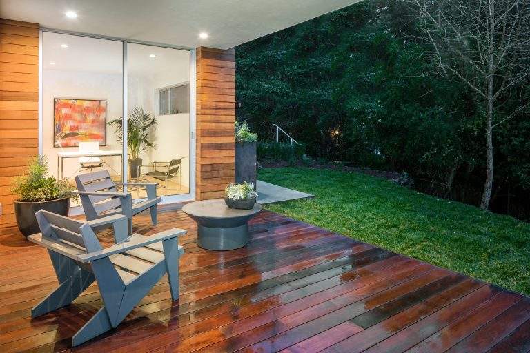 Wooden deck / balcony at night with furniture looking inside.