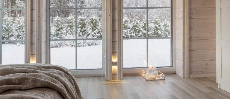 Bright interior of the room in wooden house with a large window overlooking the winter courtyard. Snowy winter landscape in white window. Home and garden, Christmas concept.